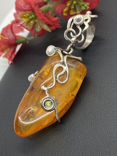 "ARTISAN AMBER GEMSTONE PENDANT Hand-made Sterling Silver. Stones used: Baltic Amber, Pearls, Peridot, Amethyst. Height - 73mm, Width - 30mm. Unique Handcrafted One-of a-kind Design Pendant Each Piece of Jewelry in my Collection is Absolutely One of a Kind! When you start wearing a piece of my jewelry you will fall in love with it more and more each day and feel that good Energy and Love that I pass into it while creating this piece of Art. A piece of Art created for you to be inspired and love Elegant Gemstone Pendant Beads, Elegant Gemstone Pendant, Amber Pendant Jewelry For Wedding, Yellow Pearl Pendant Jewelry, Fusion Style Pearl Pendant Jewelry As Gift, Fusion Style Pearl Pendant Jewelry For Gift, Unique Pendant Beads For Jewelry Making, Unique Amber Gemstone Beads And Cabochons, Unique Beads, Gems And Cabochons As Gifts