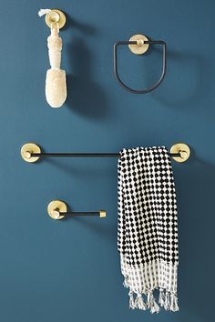 a towel hanging on a blue wall next to two black and white towels with gold handles