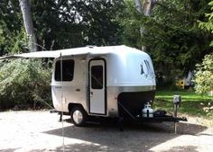 an rv is parked in the shade near some trees