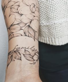 a woman's arm with flowers on it and the word love written in cursive writing