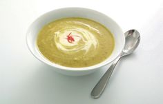 a white bowl filled with soup next to a spoon