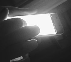 a person holding a cell phone in their hand with the light shining on them from behind