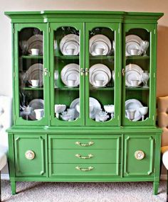 a green china cabinet with dishes on it