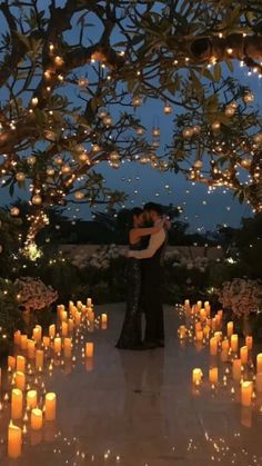 a man and woman standing under a tree filled with candles