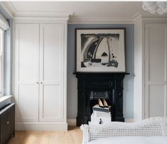 a living room with white furniture and a painting hanging on the wall over a fireplace