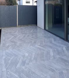 an outdoor patio with grey tiles and wooden fence