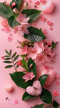 pink flowers and leaves on a pink background with heart - shaped candies around them