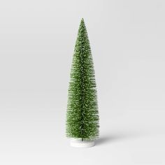 a small green christmas tree in a white vase