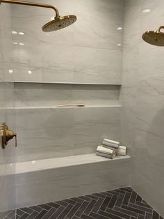 a bathroom with white marble walls and flooring, two shower heads on either side of the bathtub