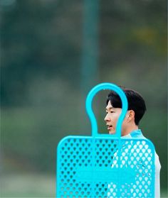 a young man holding a blue frisbee in his hand and looking at it