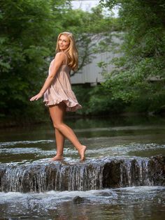 a woman standing on top of a rock in the water