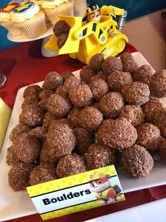 there is a pile of chocolate balls on the table next to some cupcakes