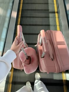 two pink suitcases sitting on top of an escalator next to each other