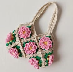 a crocheted purse with pink flowers on the front and green leaves on the back