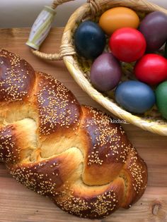 a loaf of bread next to an easter basket with eggs in it on a wooden table