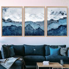 three paintings hang on the wall above a couch in a living room with a coffee table