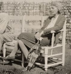 an old black and white photo of two people sitting on a bench