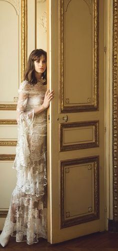 a woman standing in front of an open door wearing a dress with ruffles