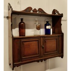 an old wooden cabinet with bottles and soaps on the top, in front of a white wall