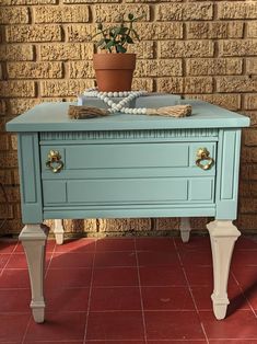 a blue table with two drawers and a potted plant on top