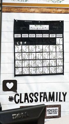 a black and white calendar hanging on the wall next to a computer monitor with text that reads class family