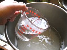 someone is pouring water into a metal bucket with red writing on the bottom and inside