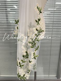 a white sheer curtain with flowers and leaves on it