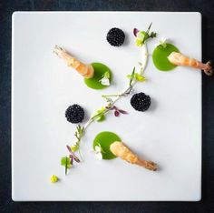 a white plate topped with food on top of a black and green table cloth covered in leaves