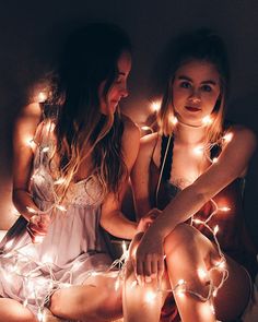 two beautiful young women sitting next to each other with lights on their backs and legs