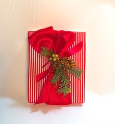 a present wrapped in red and white paper with a pine cone on top