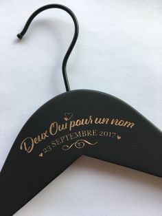 a black hanger with gold lettering on it and a heart shaped tag attached to it