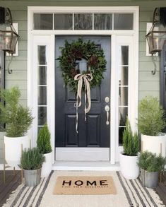 the front door is decorated with potted plants and a welcome mat that says home