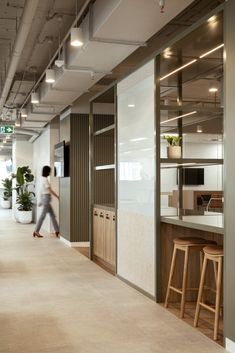 a person walking down an office hallway next to a counter with stools on it