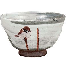 a white bowl with a bird painted on the side and red trim around the rim