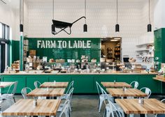 the inside of a restaurant with green walls and wooden tables, white chairs, and lots of food