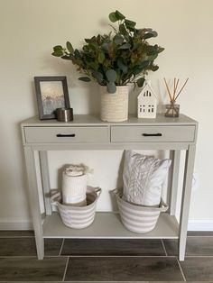 small entryway table with baskets on top and plants in the bottom, next to it