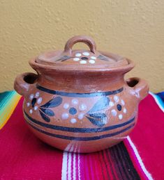 a brown pot sitting on top of a colorful table cloth