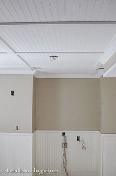 an empty room with white paneling on the ceiling and two electrical outlets in the wall