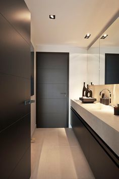 a modern bathroom with white counter tops and black cabinets, along with an open door that leads to another room