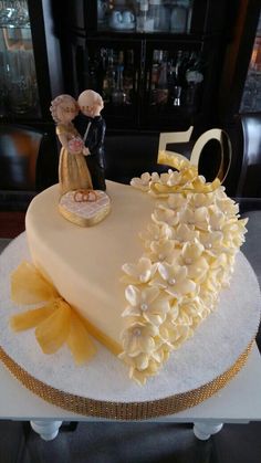 a 50th cake decorated with flowers and a figurine in the shape of a heart