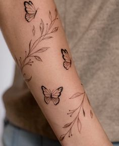 a woman's arm with butterfly tattoos on the left side of her arm and an arrow in the middle