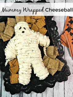 a black plate topped with crackers and marshmallows in the shape of a ghost