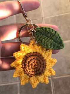 a crocheted sunflower keychain is being held by someone's hand