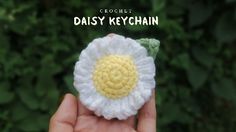 crochet daisy keychain in hand with text overlay that reads, crochet daisy keychain