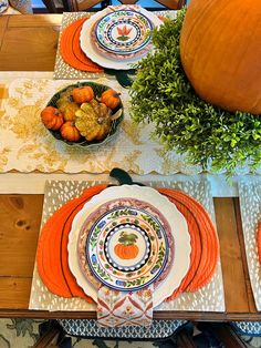 the table is set with plates and pumpkins