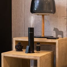 a wooden table topped with a lamp next to a remote control and other items on top of it