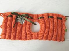 an orange knitted piece with leaves attached to it