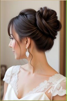 a woman with her hair in a low bun, wearing an elegant white dress and earrings