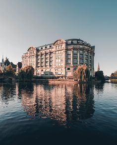 a large building sitting on top of a lake next to a tall building with many windows