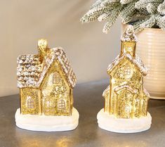 two gold christmas houses sitting on top of a table